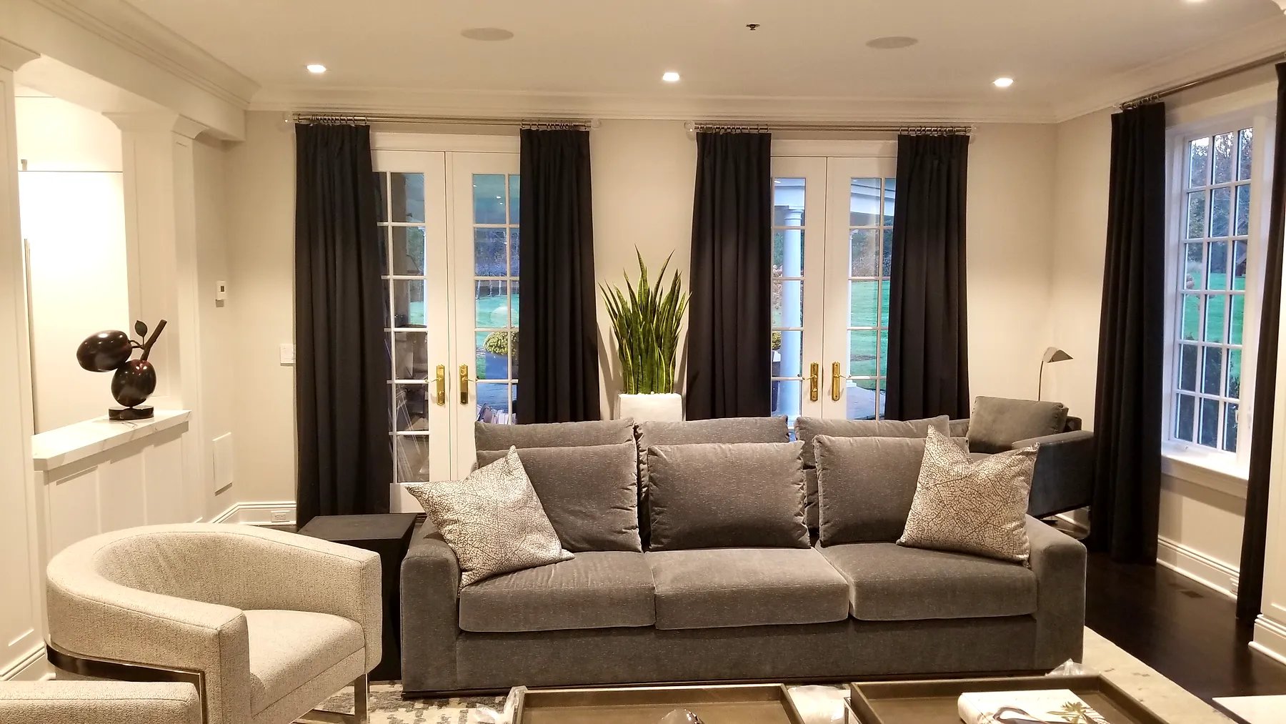 Floor-length pinch pleat drapery flanking French doors and windows in a living room