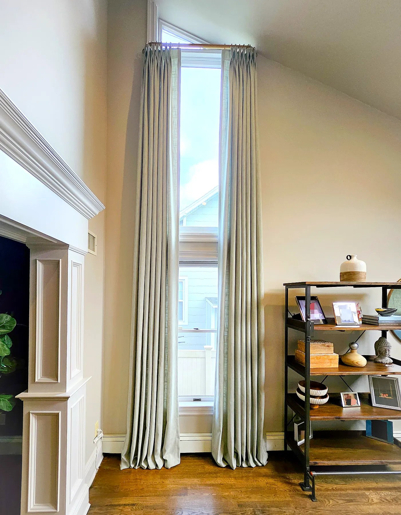 Floor-to-ceiling pinch pleat drapery on a tall narrow window in a vaulted-ceiling room