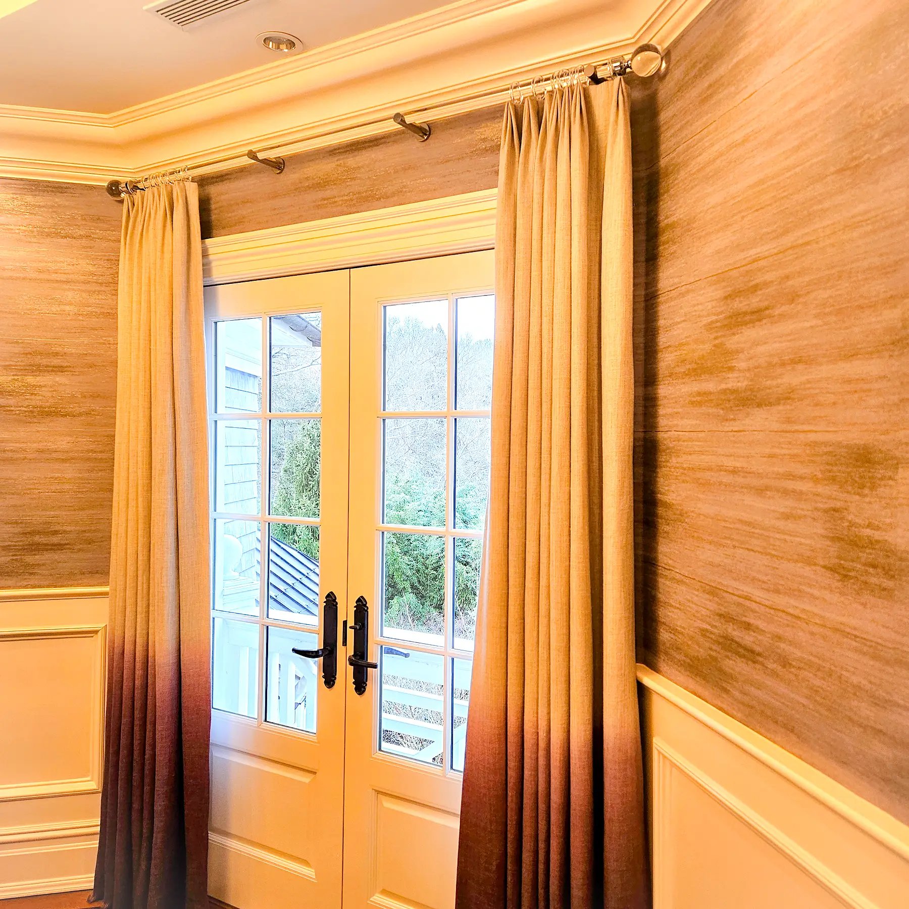 Pinch pleat drapery with ombré hem detail flanking French doors