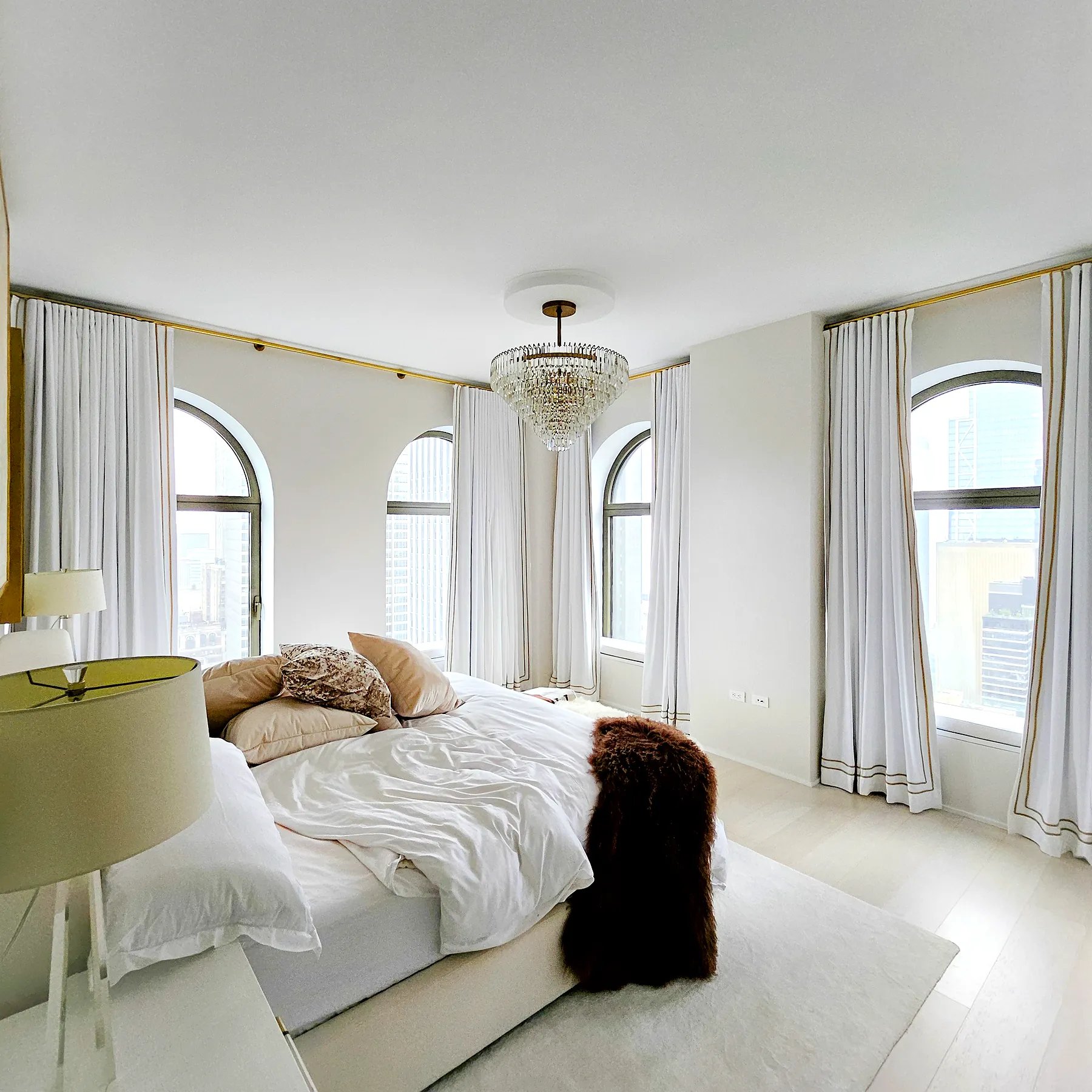 Pinch pleat drapery with horizontal tape trim across arched bedroom windows