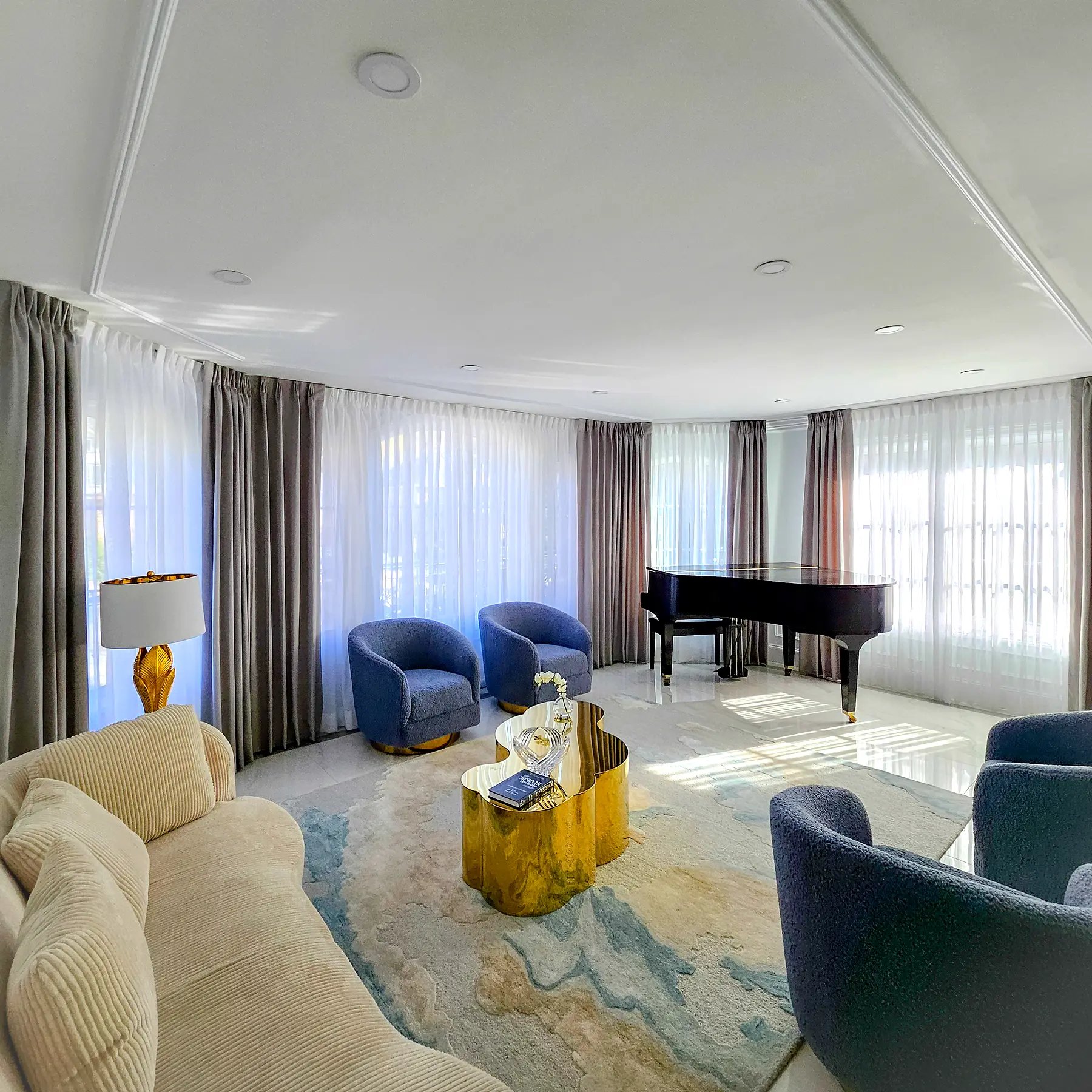Layered sheers under pinch pleat side panels across windows in a formal living room