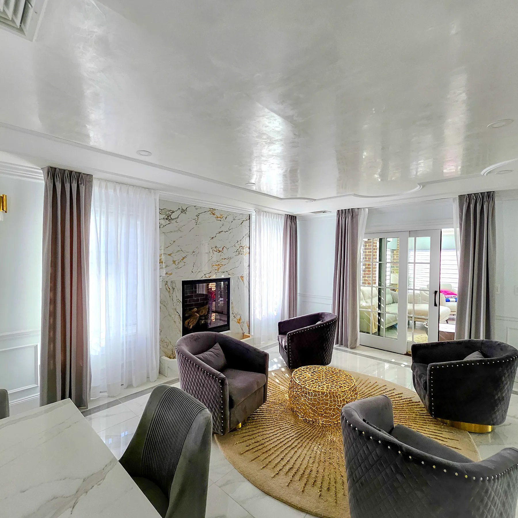 Pinch pleat side panels with sheers framing a marble fireplace in a sitting room