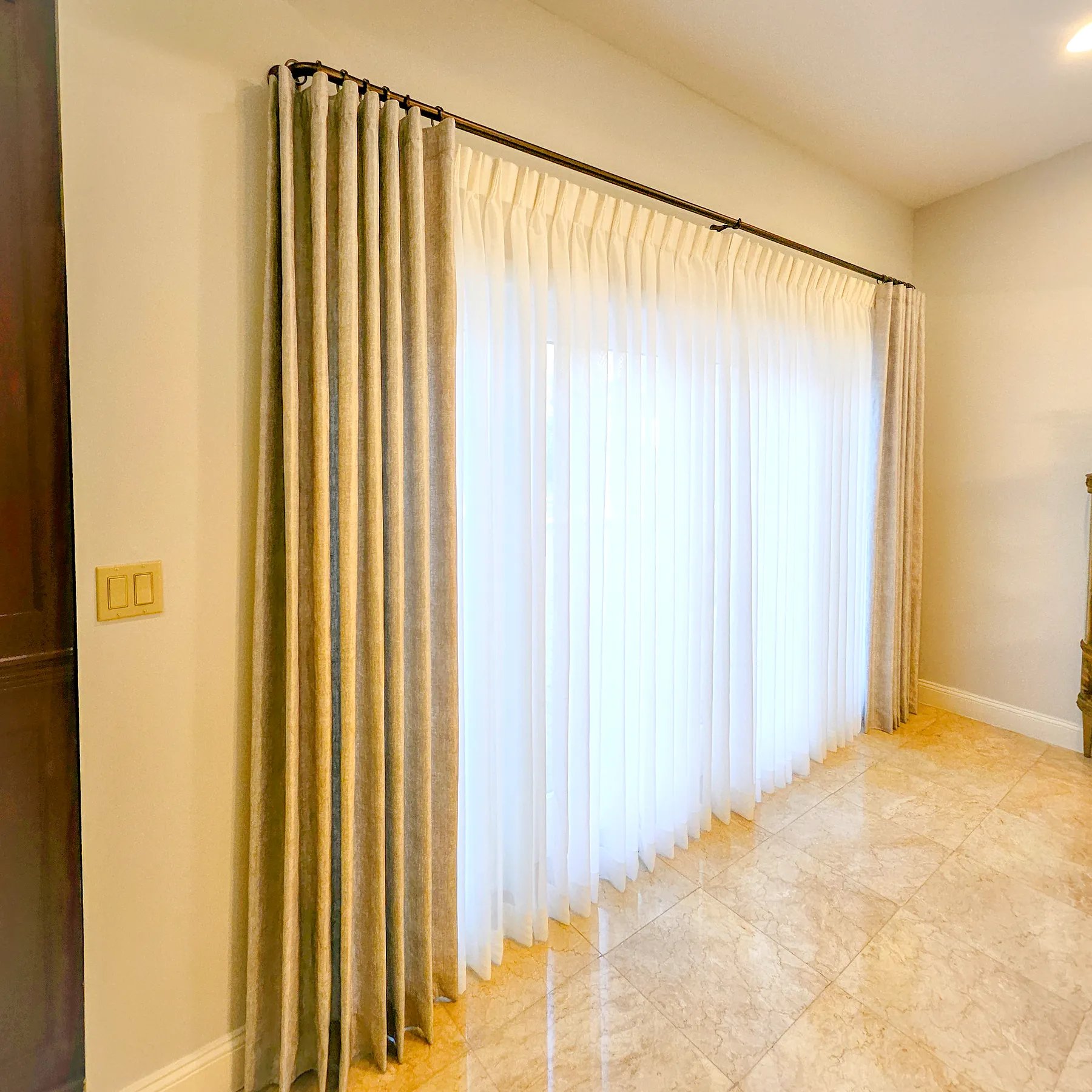 Layered drapery with sheer center panel under pinch pleat side panels on a double rod