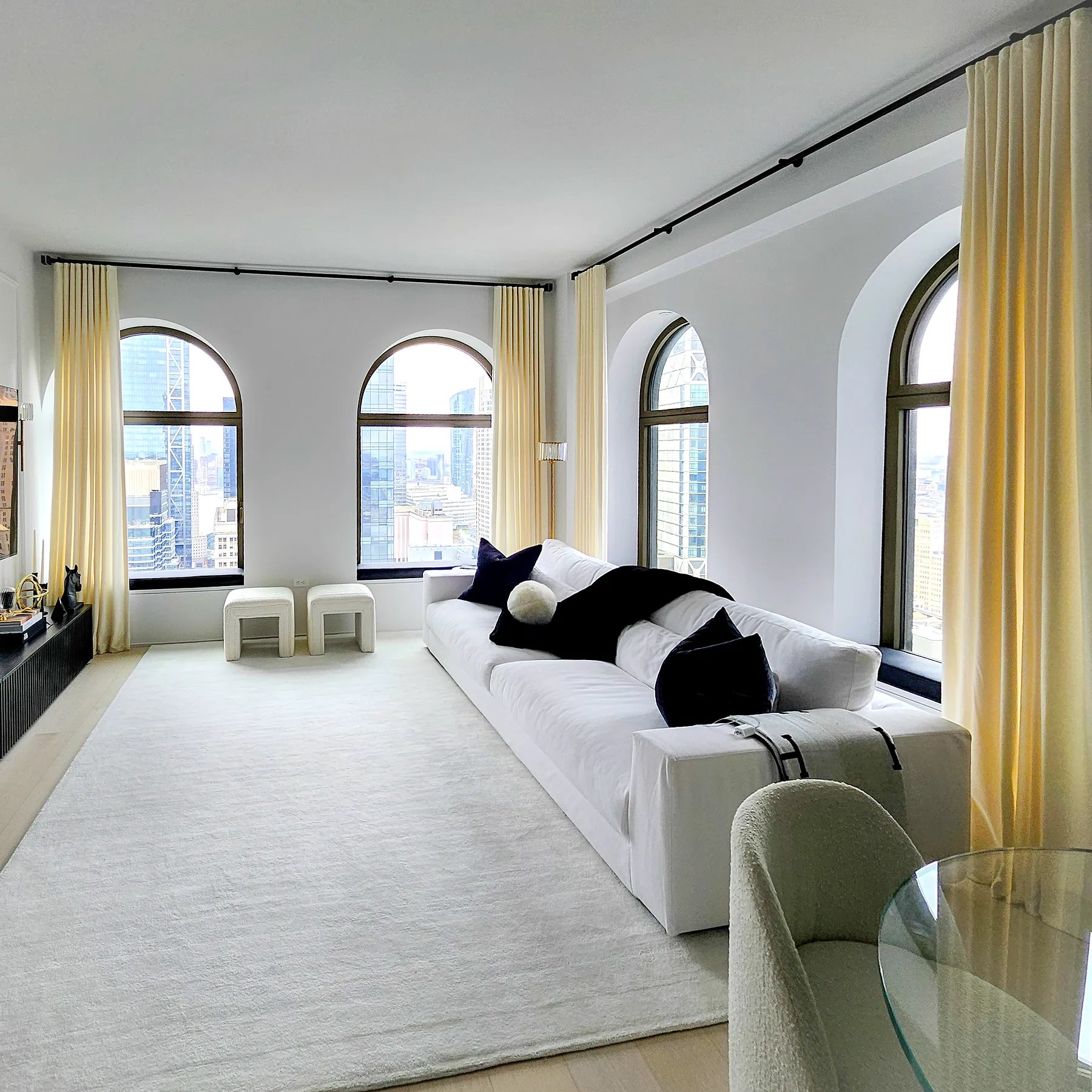 Floor-length drapery on a single long rod across arched windows in a high-rise living room