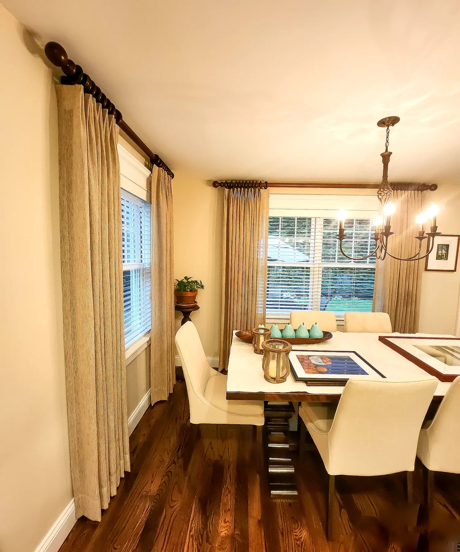 Pinch pleat drapery in a dining room layered with venetian-blind window treatments