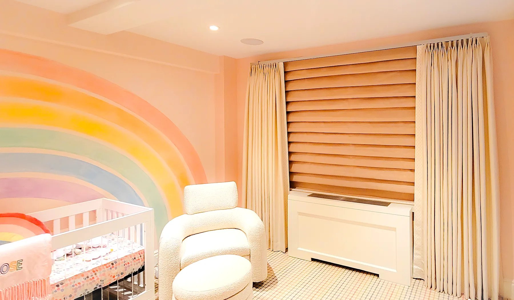 Pinch pleat drapery side panels layered over a roman shade in a modern nursery